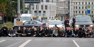 Menschen sitzen in einer Reihe auf dem Boden.