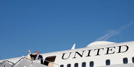 Donald Trump steht winkend an einem Flugzeug