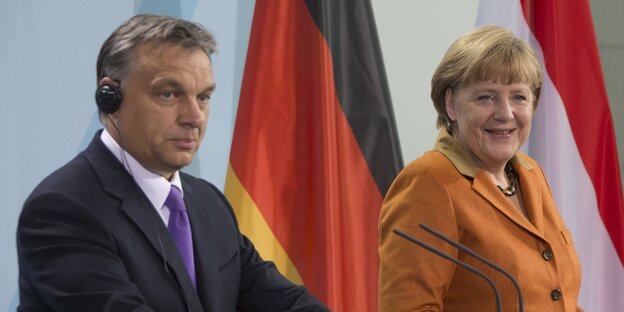 Viktor Orbán steht neben Angela Merkel an einem Pult