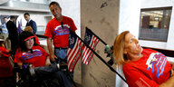 Menschen in roten T-Shirts und mit Flaggen, zum Teil im Rollstuhl sitzend, demonstrieren im US-Senat