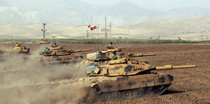 Türkische Panzer stehen in der Wüste und wirbeln Staub auf