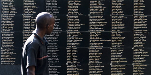 Ein Mann steht vor einer Tafel mit vielen Namen