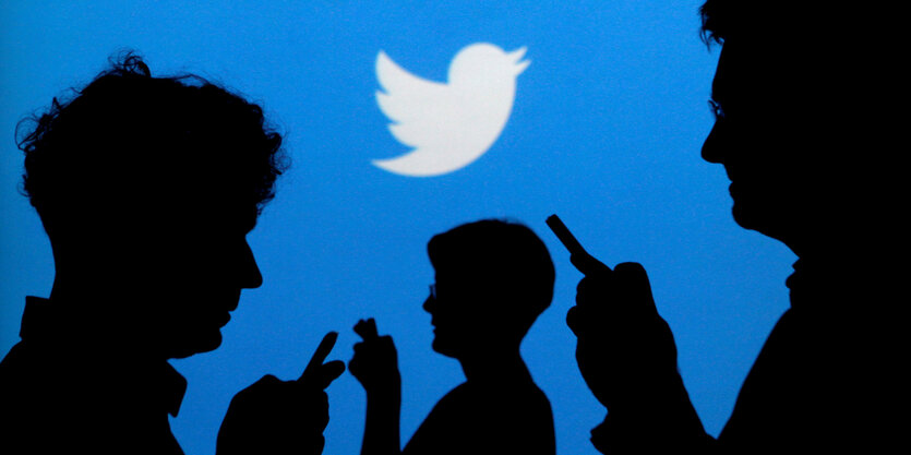 Schatten von Menschen mit Telefon vor dem Twitter-Logo