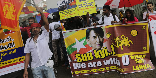 Demonstranten halten ein Schild auf dem steht "Suu kyi, we are with you"