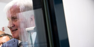 Horst Seehofer steht hinter einer spiegelnden Glaswand