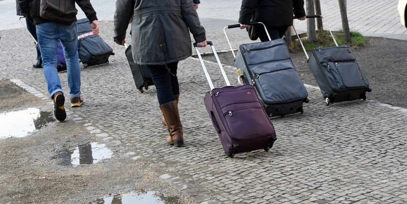 Menschen laufen mit Rollkoffern