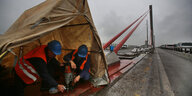 Zwei Bauarbeiter unter einem Zelt arbeiten auf einer Brücke