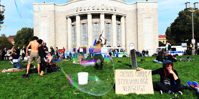 Menschen mit Schildern und Seifenblasen vor der Volksbühne