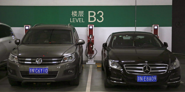 Zwei Wagen mit Verbrennungsmotoren stehen auf Parkplätzen für E-Autos in einem Einkaufszentrum in Peking.