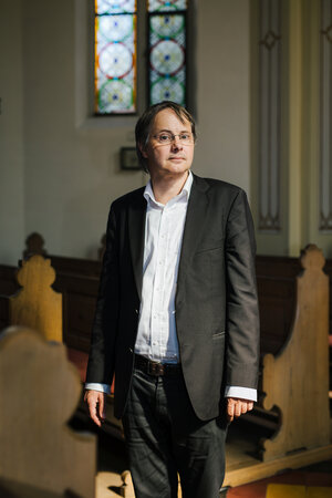 Ein Mann steht vor Kirchenbänken Ein Mann steht vor Kirchenbänken