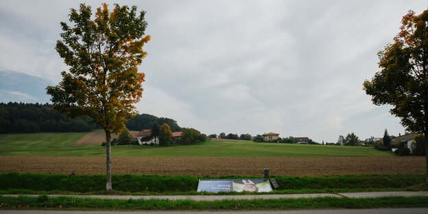 Ein umgefallenes Plakat vor einem Dorf Ein umgefallenes Plakat vor einem Dorf