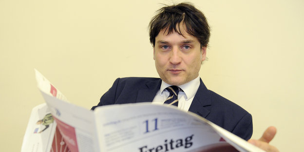 Jakob Augstein hält eine Ausgabe der Wochenzeitung "Der Freitag" aufgeschlagen in den Händen