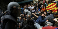 Menschen liegen auf dem Boden in Barcelona. Ein Polizist steht im Vordergrund