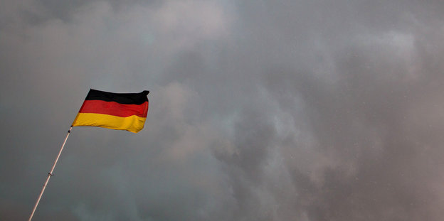 Eine Deutschlandfahne vor Gewitterwolken
