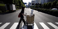 Eine Frau schiebt einen Roboter in einem Wagen über eine Straße