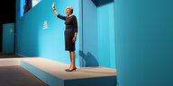 Eine Frau in einem Kleid steht vor einer blauen Wand