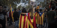 Zwei Frauen laufen Arm in Arm mit einer Katalonien-Flagge durch eine Menschenmenge