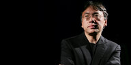 Der Autor Kazuo Ishiguro steht vor schwarzem Hintergrund