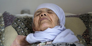Die 106-jährige Geflüchtete Bibihal Uzbek liegt auf einem Bett