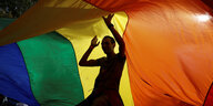 Ein Mann tanzt unter einer Regenbogenflagge