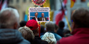 Menschen halten ein Foto der AfD-Spitzenkandidaten Alice Weidel und Alexander Gauland und die Worte Holen wir unser Land zurüc