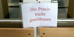 An einer Tür steht ein Schild mit der Aufschrift "Die Praxis bleibt geschlossen".