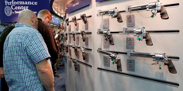 Männer sehen sich in einem Geschäft Schusswaffen an