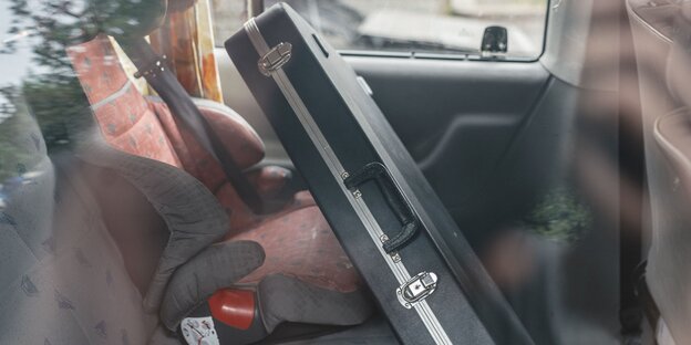 Ein Gitarrenkoffer steht auf dem Rücksitz eines Autos Ein Gitarrenkoffer steht auf dem Rücksitz eines Autos