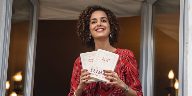 Leïla Slimani zeigt lachend ihr Buch am Fenster des Drouant Restaurants in Paris
