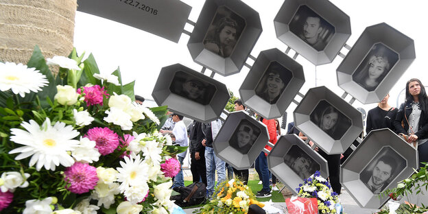 Besucher legen Blumen am Denkmal in München nieder