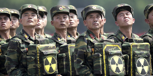 Nordkoreanische Soldaten tragen Taschen vor dem Bauch, die das Zeichen für Radioaktivität ziert