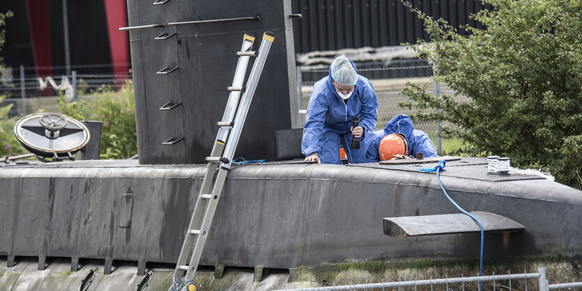 Menschen in blauen Anzügen klettern in ein U-Boot