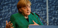 Angela Merkel gestikultiert an einem Pult