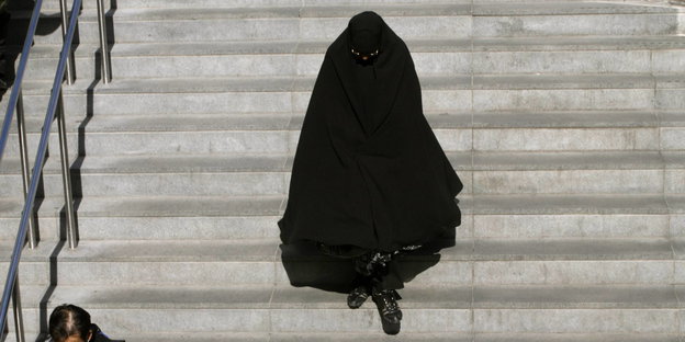 eine Frau in Burka geht eine Treppe hinunter