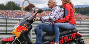 Ein Mann fährt mit einer Frau als Beifahrerin auf einem Red Bull-Motorrad