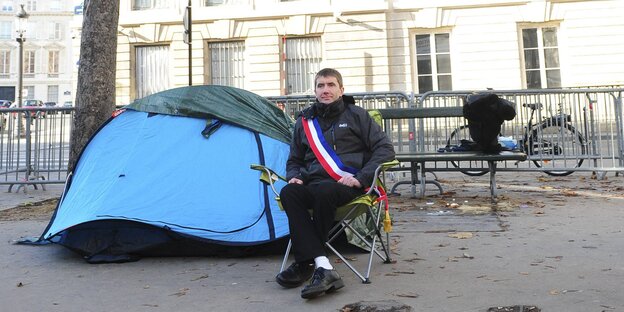 Ein Mann sitzt vor einem Zelt