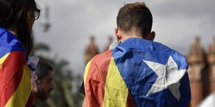 ein Mann und eine Frau, eingehüllt in katalanische Unabhängigkeitsflagge