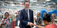 Entwicklungshilfeminister Gerd Müller schüttelt Frau die Hand.