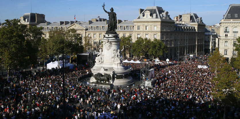 Viele Leute auf einem Platz, in der Mitte ein Denkmal