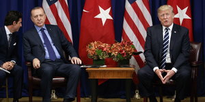 Erdoğan und Trump sitzen vor Flaggen