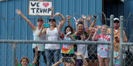 Menschen winken hinter einem Stacheldrahtzaun und halten ein "We love Trump"-Schild in die Höhe