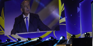 Ein Mann, Benjamin Netanjahu, an einem Pult und auf einer Leinwand
