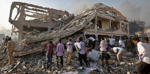 menschen sichen in Mogadischu am Anschlagsort nach Verschütteten