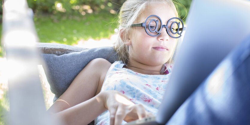 Mädchen mit witziger Brille vor einem Laptop