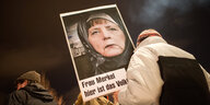 Pegida-Demonstrantin trägt Plakat, das Merkel mit Kopftuch zeigt