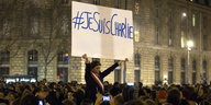 eine Frau hält in einer Menschenmenge ein Schild mit #JeSuisCharlie hoch