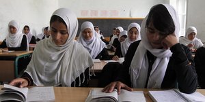 Mädchen mit aufgeschlagenen Büchern in einem Klassenzimmer