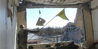 ein Sodat mit einer Fahne in der Hand in einem völlig ausgebombten Haus