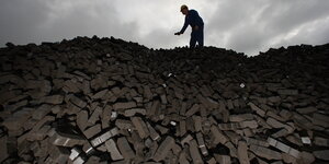 Ein Arbeiter auf einem Berg aus Kohlebriketts