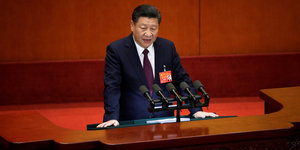 Ein Mann, Xi Jinping, steht an einem Rednerpult